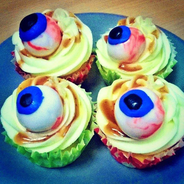 Gory looking Halloween cupcakes with eyeball toppings Vanilla frosted cupcakes in red and green cases with eye ball decorations