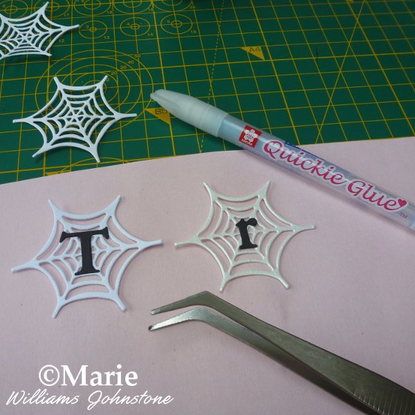 Adding letters to the middle of paper spider webs to spell a Halloween phrase