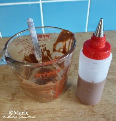 Melted chocolate in a glass jug with a half filled icing bottle