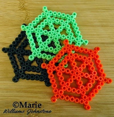 Webs made from perler beads in black, green and orange