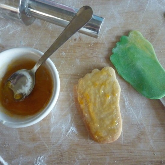 Sticking the rolled fondant to the sugar cookies using apricot preserve apricot preserve in a pot along with a rolling pin and cut sugar cookies