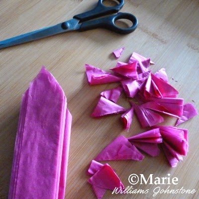 Cutting the folded pink paper with scissors