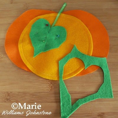 A felt pumpkin with green leaf pinned on