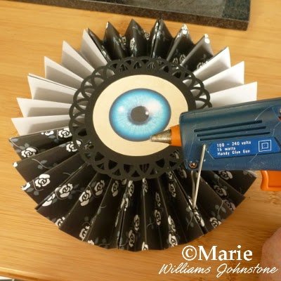 Glue gun and eyeball design attached to round paper folded hanging decor
