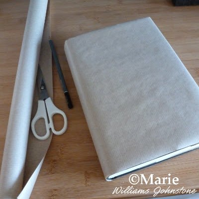 Brown paper roll witch scissors and pencil to cover book