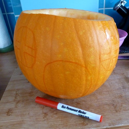 Drawing design onto a pumpkin before carving it for Halloween