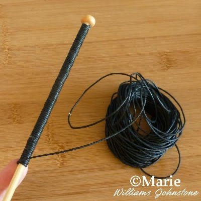 Black leather cord being wrapped around a wooden stick