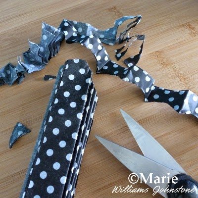 Using scissors to cut the point of the paper into a rounded shape