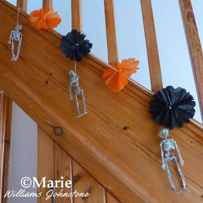 Orange and black tissue decoration hung on the staircase with skeletons