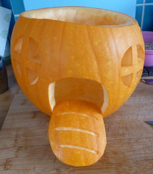 Orange pumpkin with door and windows carved into it
