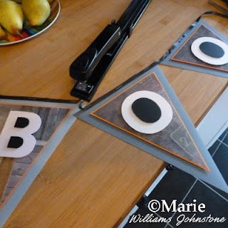 A stapler is fixing black ribbon to the top of the pennant flag bunting sections